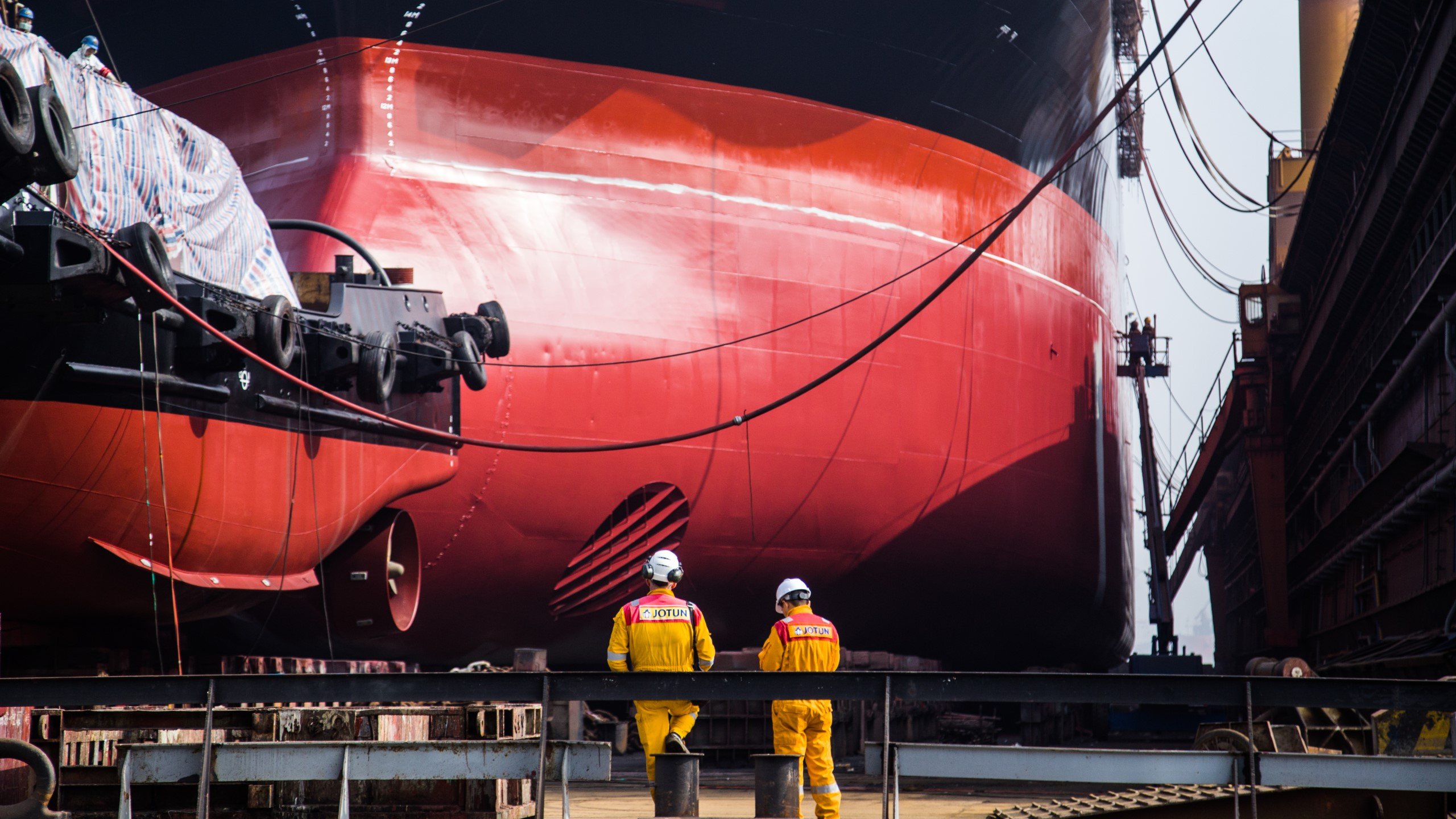 Photo of red painted hull and two workers standing in front