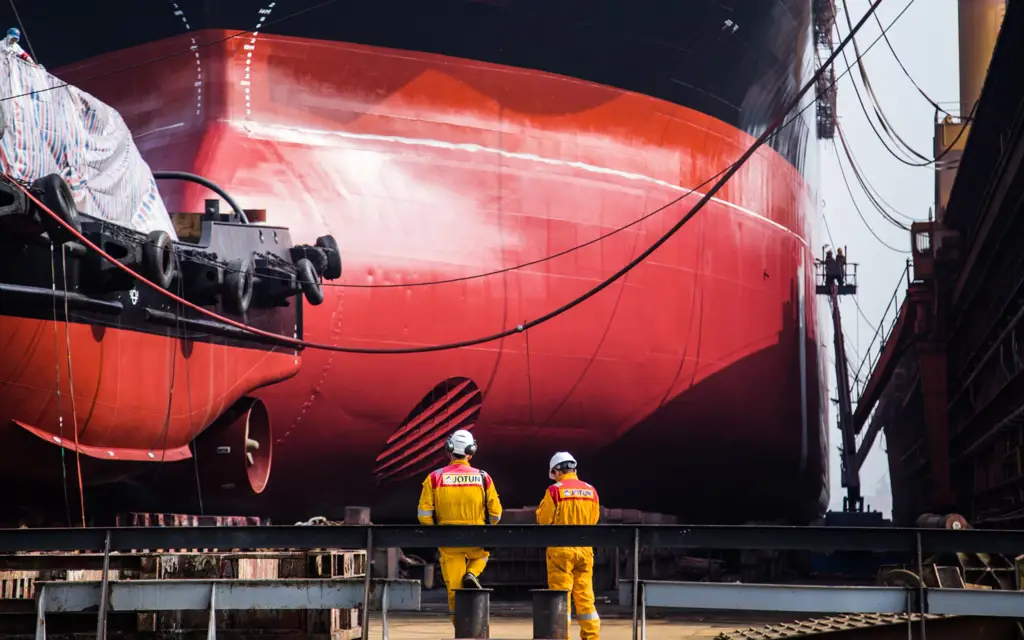 Photo of red painted hull and two workers standing in front
